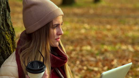 Beautiful Girl, Autumn in the Park, Drinking Coffee and Looking at the Laptop Screen