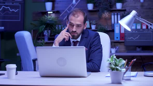 Businessman Reading Some Exciting News Late Night in the Office