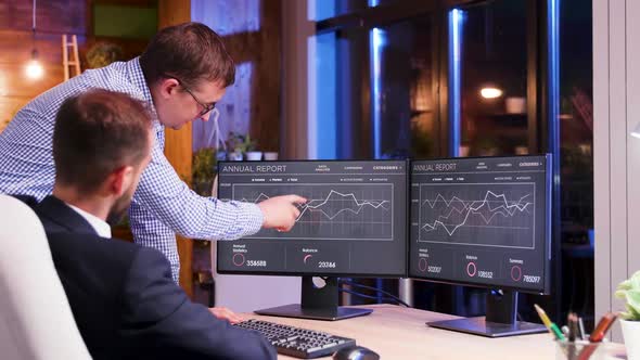 Businessman in Suit Talking with Adviser About Graph at Late Night Hours in the Office