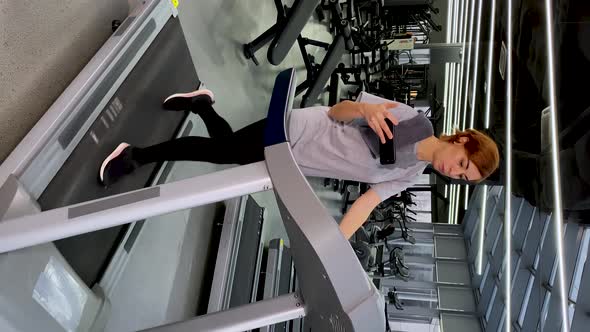 Young Woman Doing Speedwalk on Treadmill Looks at Smartphone Then Shocked and Excited