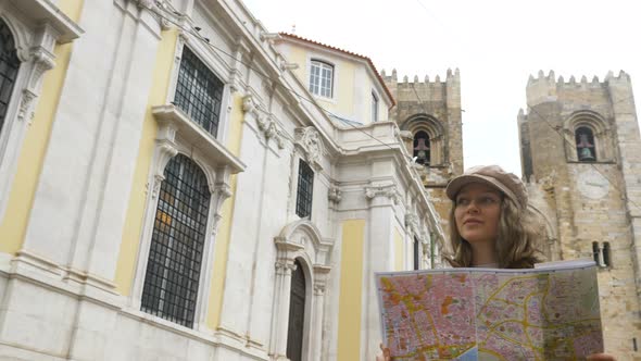 Woman Walks Along Street Holding Map and Enjoying Buildings