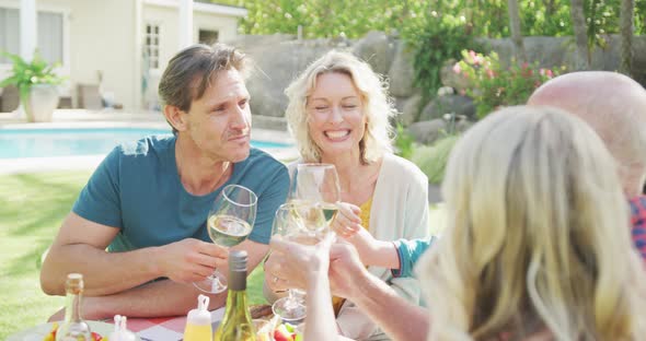 Happy caucasian family having dinner and drinking wine in garden