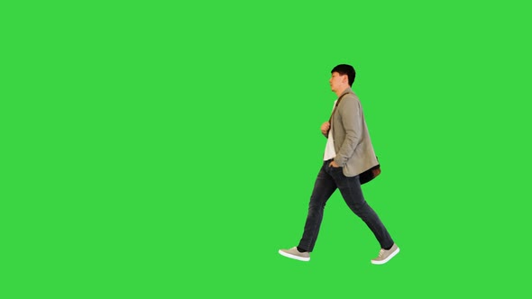 Young Asian Man Walks with Bag Across His Shoulder on a Green Screen Chroma Key