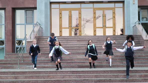 Junior Children in Uniform with Backpacks Run Down Steps