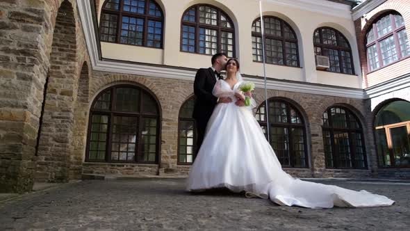 The Bride in a Long Dress Hugs and Kisses the Groom a Date