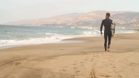 A surfer looking out towards the ocean while holding his surfboard