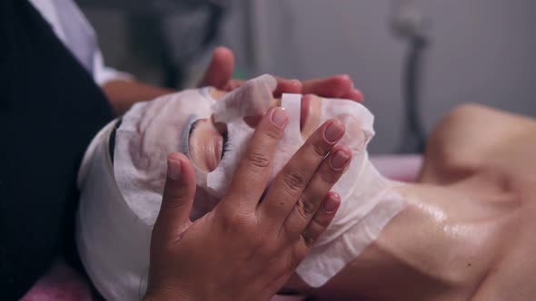 Professional Cosmetologist Holding Her Hands on Woman's Face While Apllying Special Mask on Female