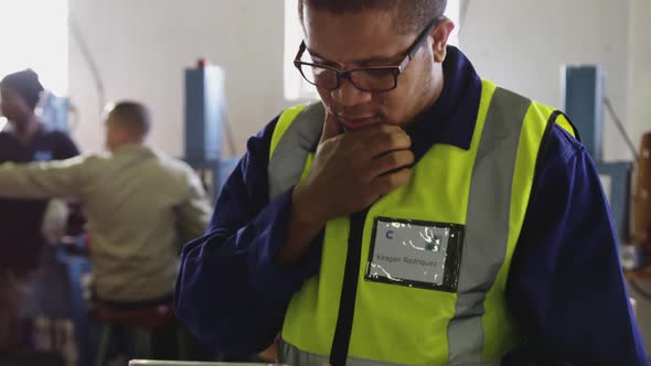 Mixed race man using tablet computer in factory