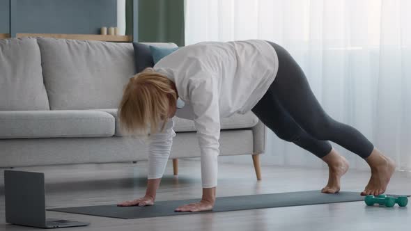 Senior Lady Doing Yoga Stretching Having Online Lesson At Home