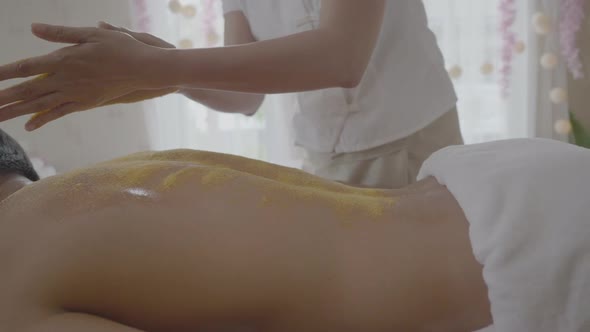 Young Man getting a salt scrub treatment at the spa aromatherapy