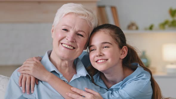 Happy Relaxed Granddaughter Embracing Older Adult Granny Cuddling Bonding Rest on Couch at Home