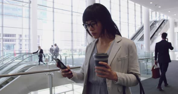 Businesswoman using mobile phone and walking in the lobby at office 4k