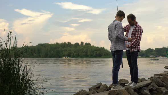 Father and 16 Years Old Son Preparing Fishing Rods, Relaxing Together Near Lake