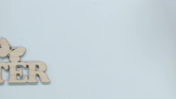 Female Hands Putting Happy Easter Wooden Inscription on Table Greeting With Fest