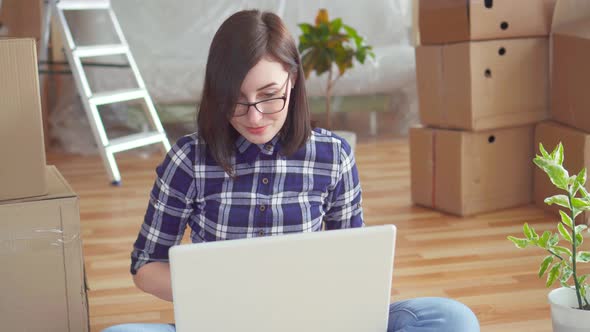 Young Woman with Laptop on Background of Boxes and Construction Works