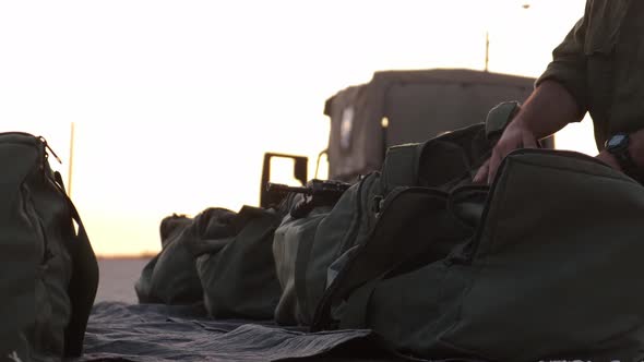 Close-up of soldiers hands prepare his equipment in his military bag ready to war at the sunset