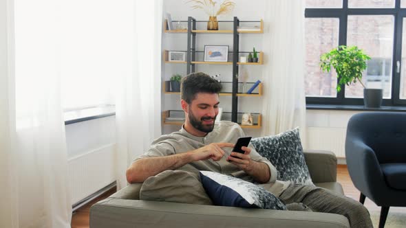 Happy Man with Smartphone at Home