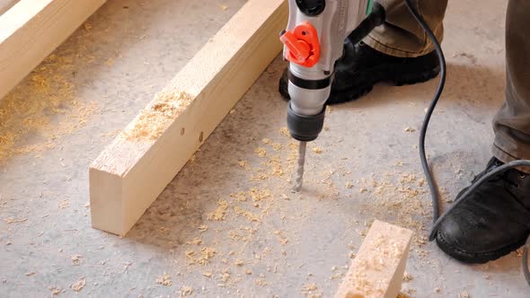 Drilling holes in the concrete floor of the house with a puncher drill for the installation of woode