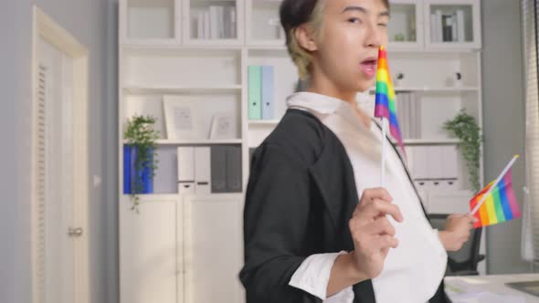 Portrait of Asian businessman gay working in office, holding LGBT flag.