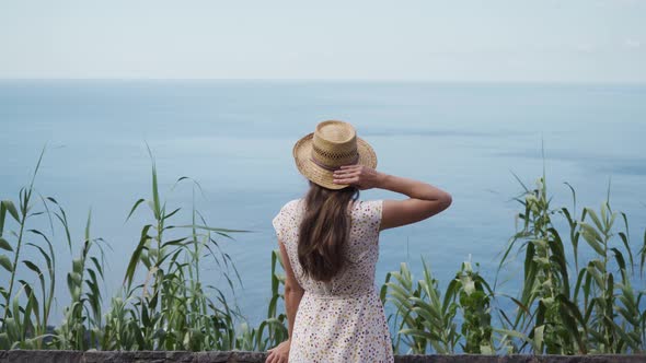 A young girl traveling on vacation arrived at a viewing point, to look at the blue ocean.