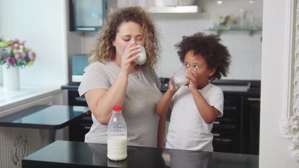 White Mother and Her Mixed Black Daughter Drinking Milk at the Kitchen