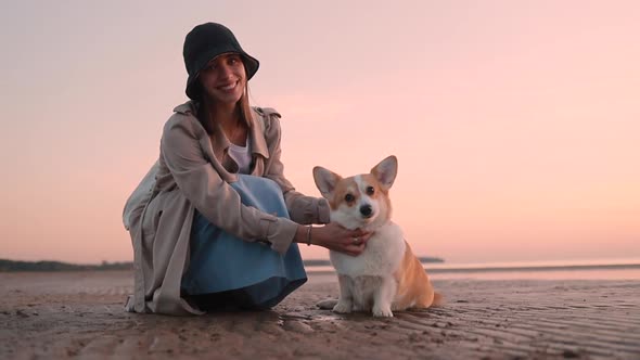 Woman and Corgi Pet Posing and Sitting on Sea Beach During Evening Sunset Outside Spbi