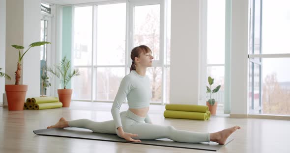 A Beautiful Woman Practices a Position of Yoga in Bright Studio Morning Concept