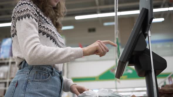 Young Woman Weighs Avocados in Plastic Bag in Supermarket