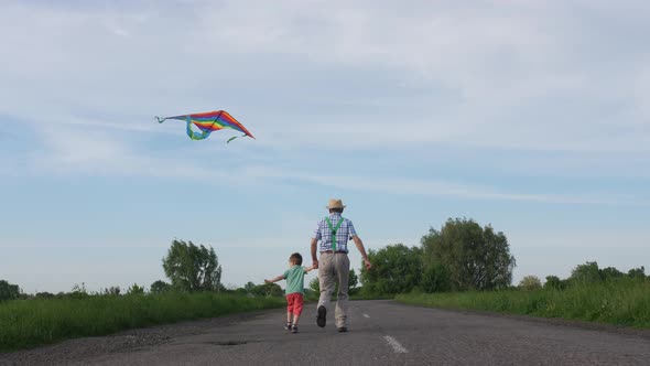 Grandpa with Grandson Flying Kite in Countryside