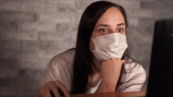 A Woman in a Medical Mask Learns News About the Coronavirus From the Internet Using a Laptop