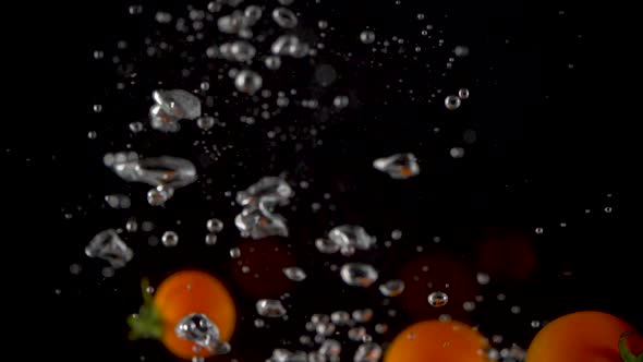 Closeup of fresh and health cherry tomatoes falling into clear water with big splash