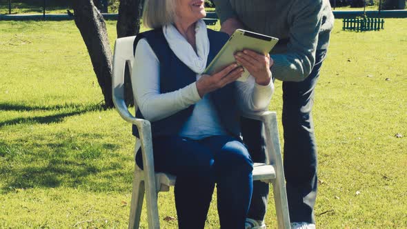 Elderly Couple Relaxing Outdoor Using Tablet