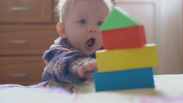 Surprised Baby Looks at Tower of Color Cubes on Soft Bed