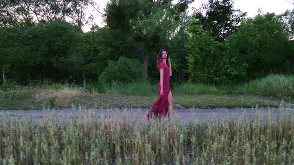 Young Woman with Long Hair in Long Dress Walks on a Field Road, Slow Motion  Shot