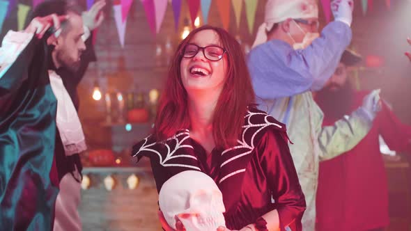 Young Beautiful Teenage Girl in a Witch Costume Holds a Skull in Her Hands