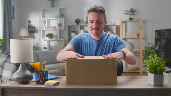 Handsome Young Man Enters His Living Room with Cardboard Box Package