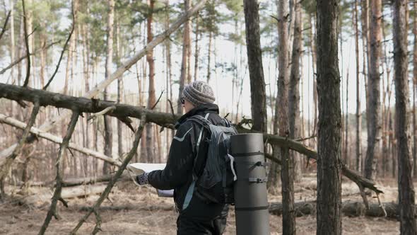 Orienteering in the forest. Tourist on a hike in a forest park with a map.