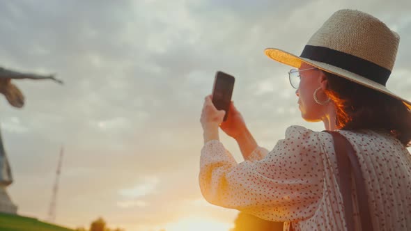 A young tourist in a hat taking a photo of the Motherland on the Mamayev Kurgan