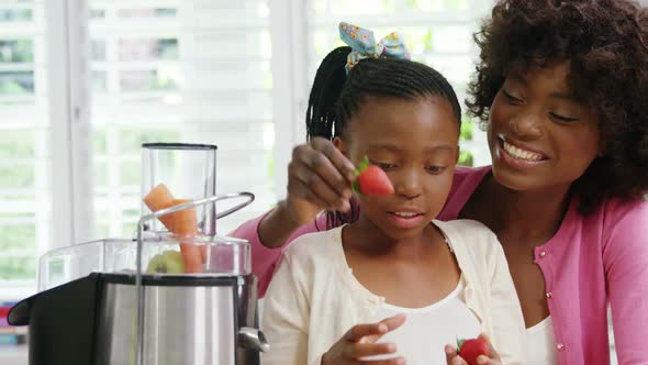 Mother and daughter putting strawberries in juicer