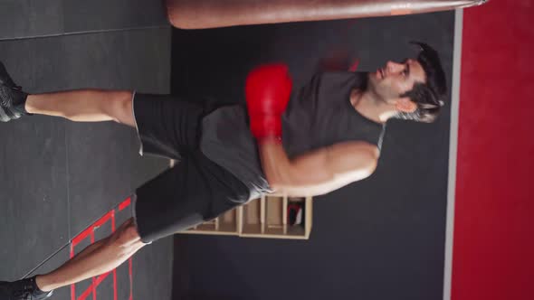 Vertical shot of active Caucasian sportsman workout, exercise doing boxing or Muay Thai.