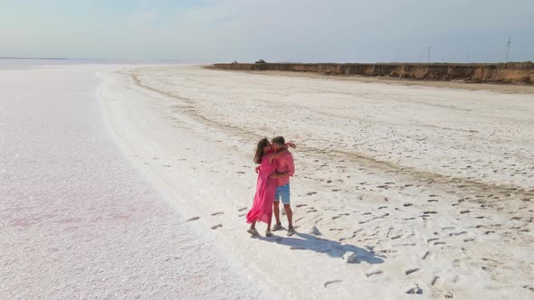 Aerial Drone Footage of Happy Joyful Couple Having Fun and Walking on Bright Colorful Pink Water of