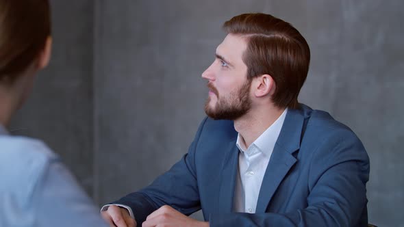Young man in a suit listening to a corporate leader at a meeting