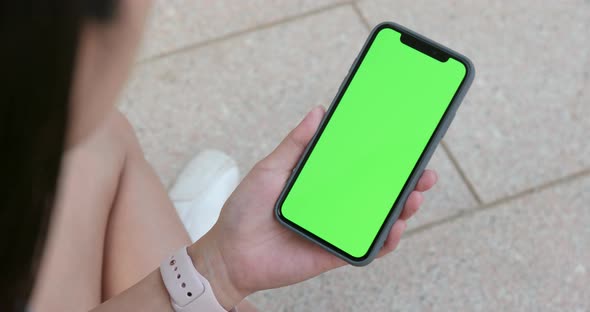 Woman holding cellphone with green screen