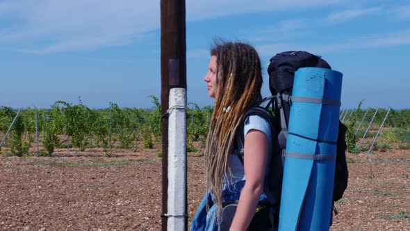 Girl with Dreadlocks Goes Past Vineyards