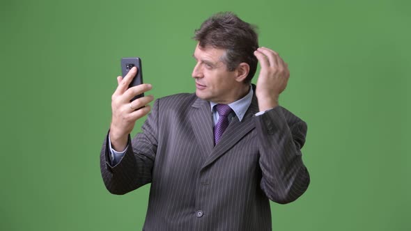 Mature Handsome Businessman Against Green Background