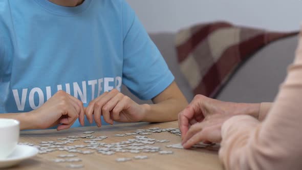 Young Volunteer and Senior Woman Doing Puzzle in Nursing Home, Leisure Activity