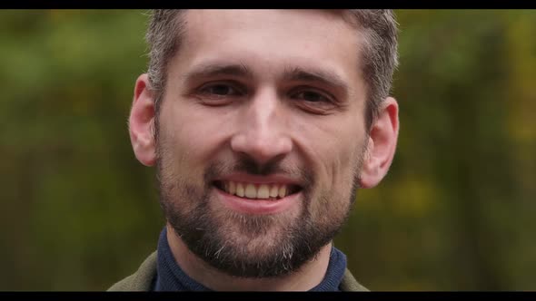 Extreme Close-up of a Smiling Handsome Caucasian Man with Brown Eyes Standing in Forest and Smiling