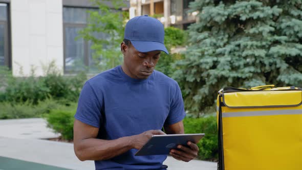 African Deliveryman Worker Employee in Blue Uniform Confirm Online Client Order