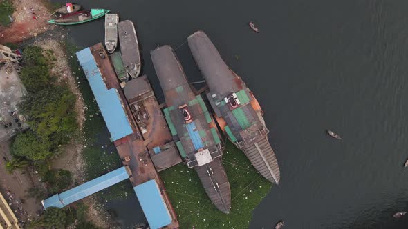 Wheel steamers at the pier in the Buriganga river bank with boats - aerial descending shot