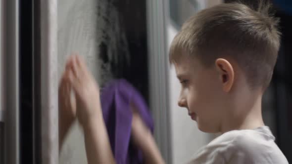 Sanitary day at home and apartment cleaning theme. Cheerful Caucasian boy 8 years old wipes off the 